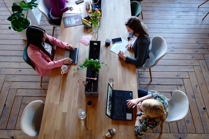 Three woman sitting around a table in a co-working space