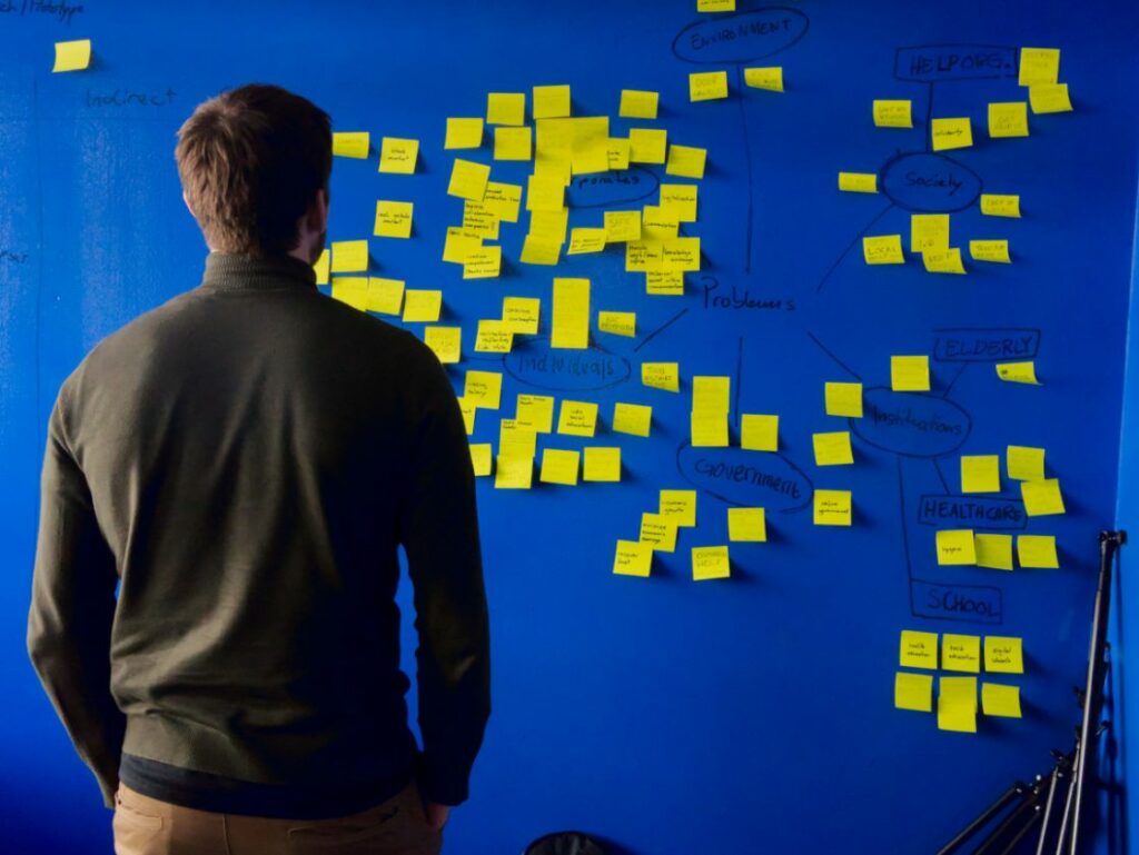 Man staring at a wall full of post it notes