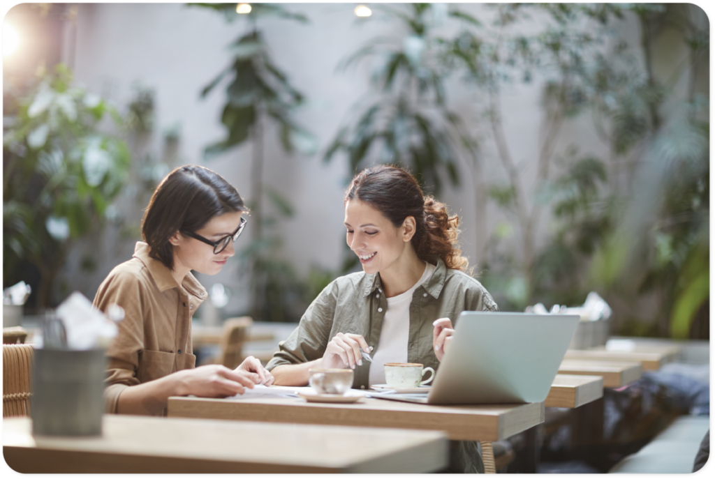 Two women sitting in a coffee shop to work.